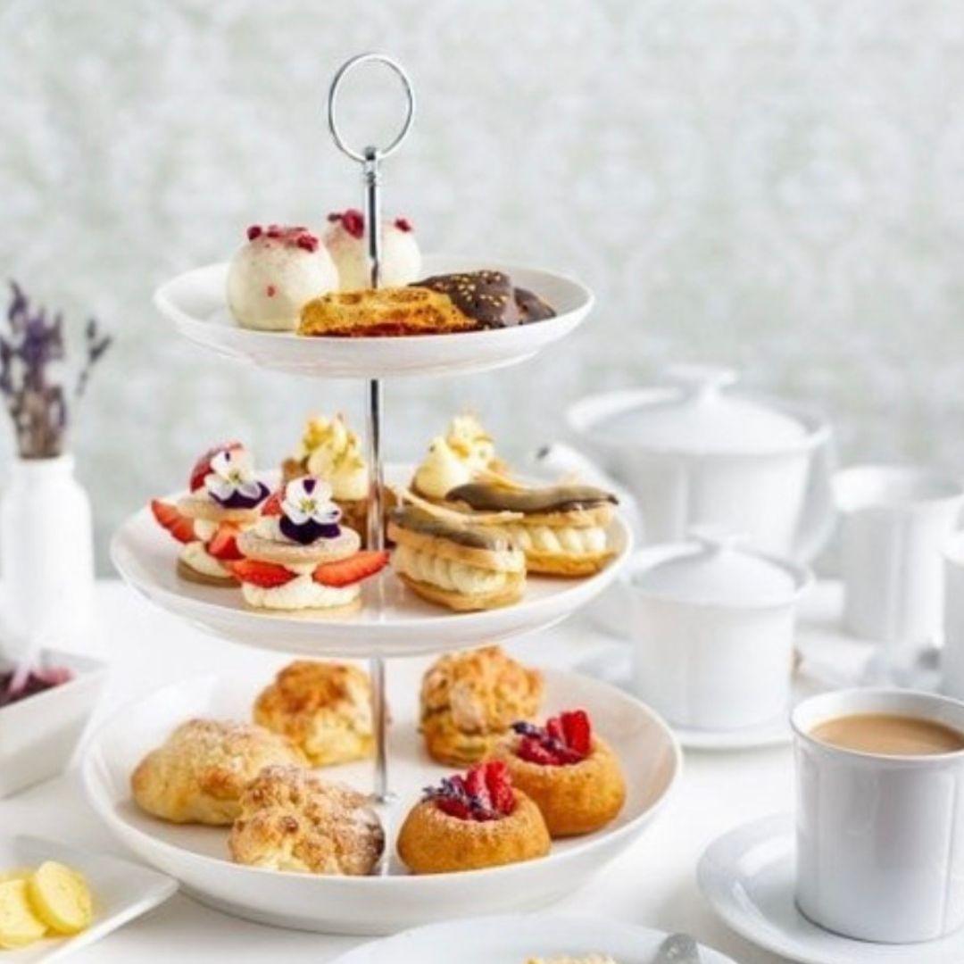 tea pot and cup with tiered stand full of baked goods