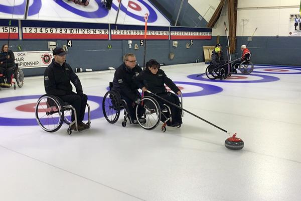 Three athletes playing Wheelchair Curling.