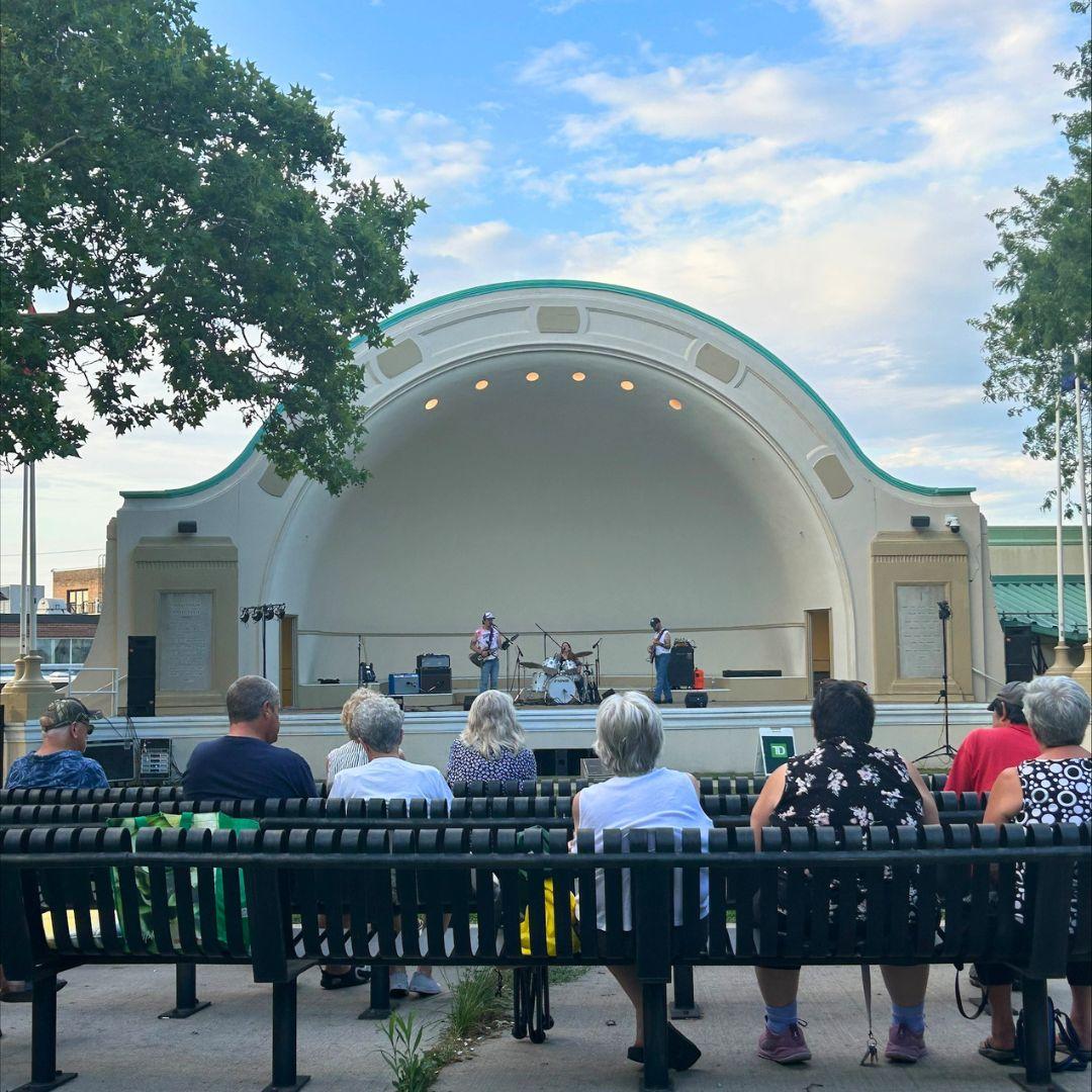 outdoor bandshell with audience seated on benches
