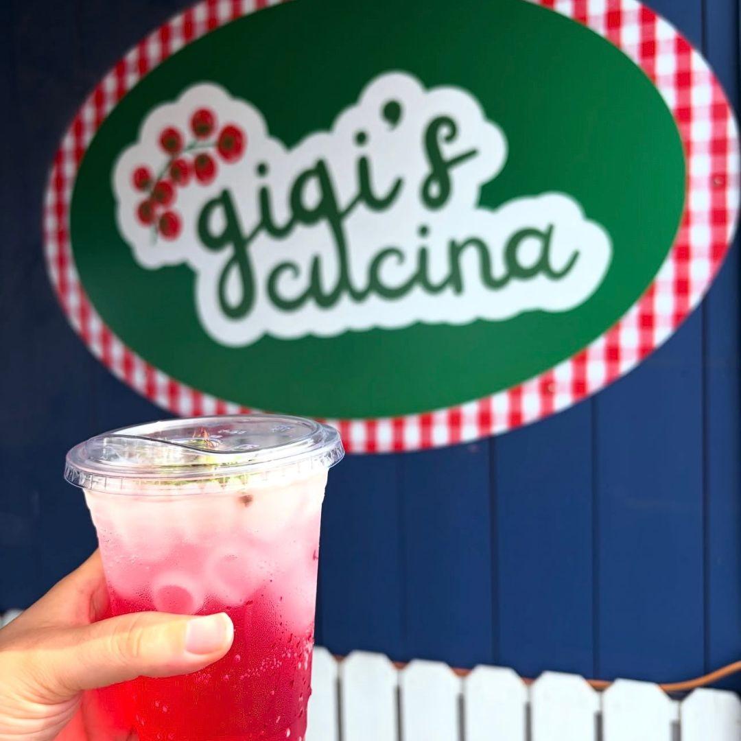 hand holding a drink up to a sign