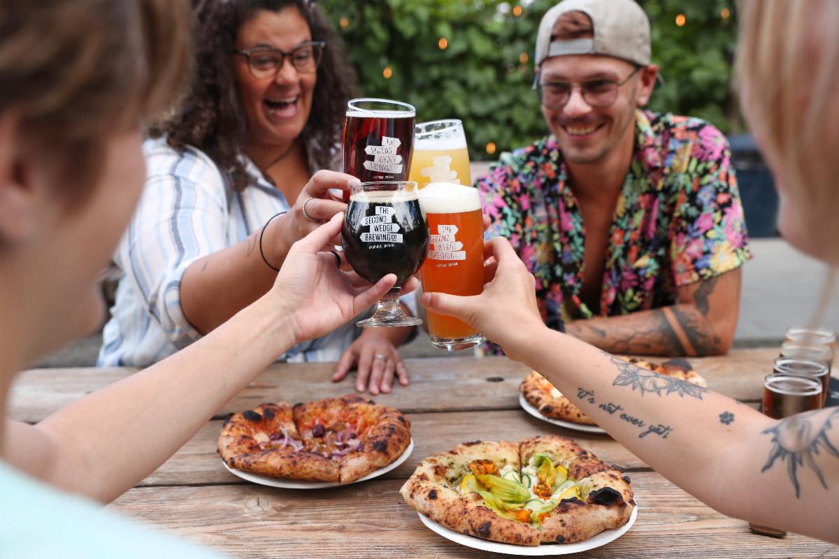group of four people seated at a table celebrating with drinks over plates of food.