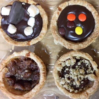 Four butter tarts on a wooden board.