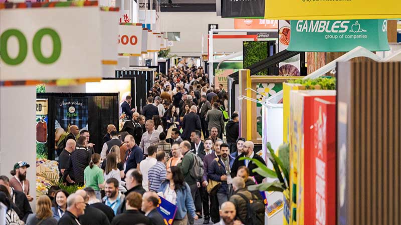 crowd of people walking past trade booths