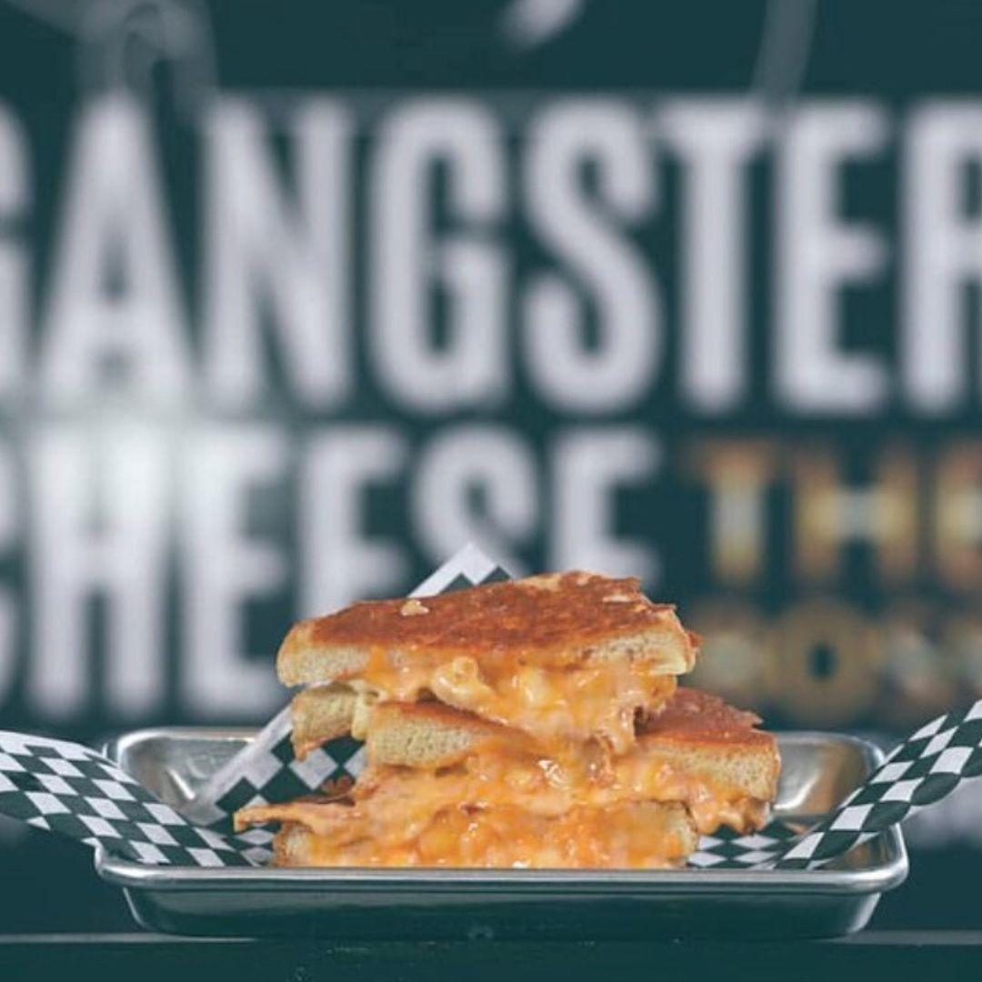 grilled cheese sandwich with Gangster Cheese logo behind