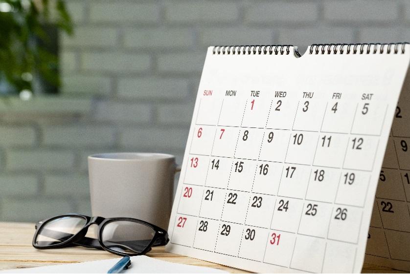 A paper calendar on a calendar with some glasses and a mug