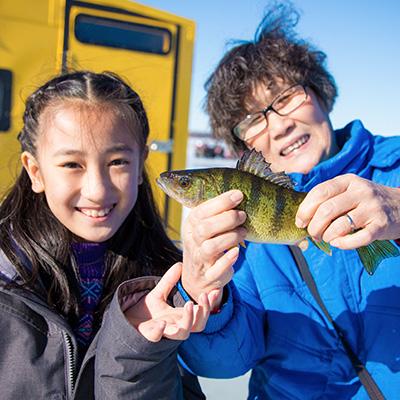 A young girl and her mother   ice fishing.