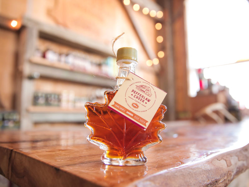 Maple syrup in a male leaf shaped bottle sitting on a counter