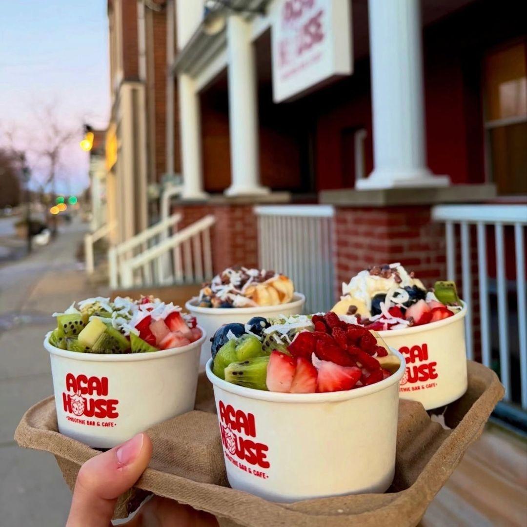a hand holds up a tray holding four fruit bowls 