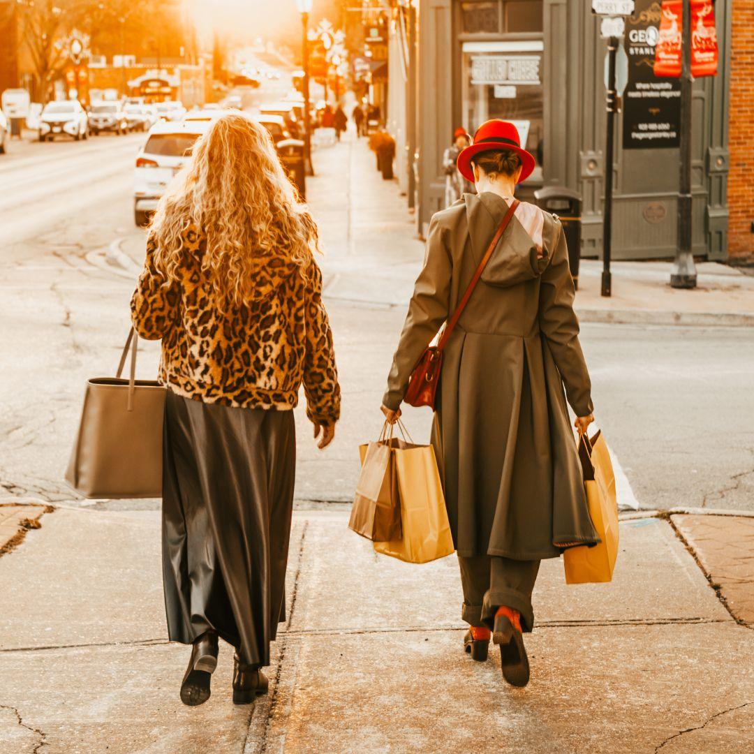 two women walking down a street carrying shopping bags