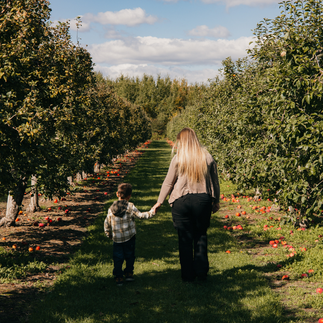 woman and child walking through apple orchard