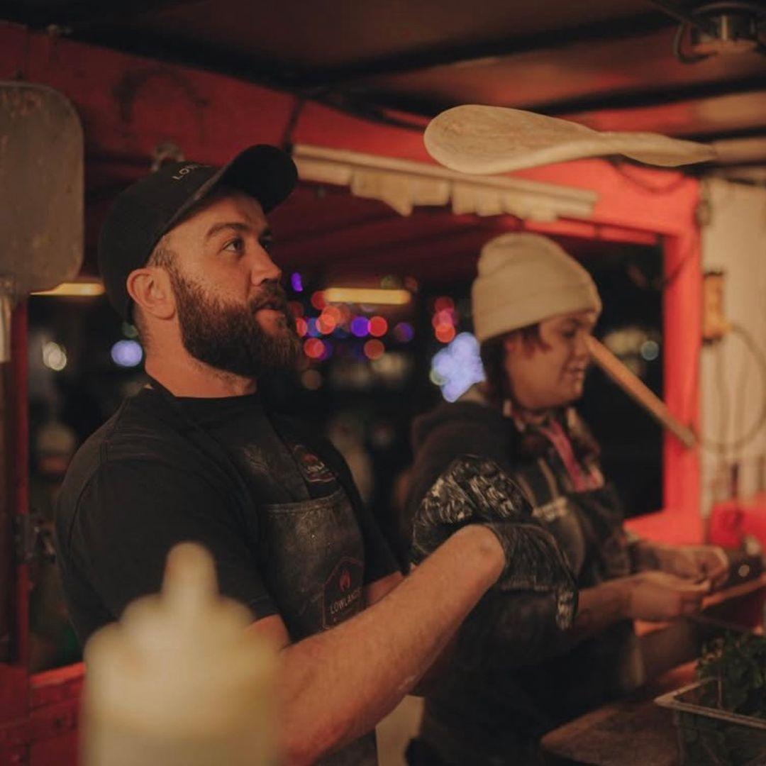 A man throwing pizza crust in the air.