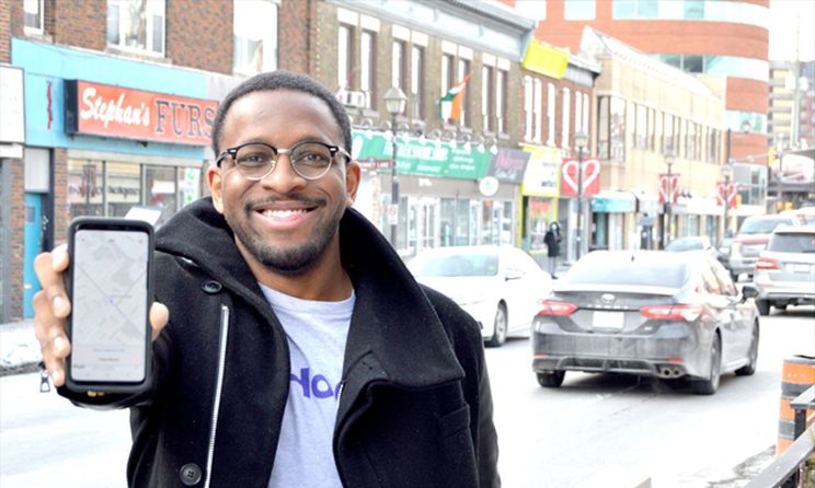 Boyd Reid standing by street holding a cell phone towards the camera