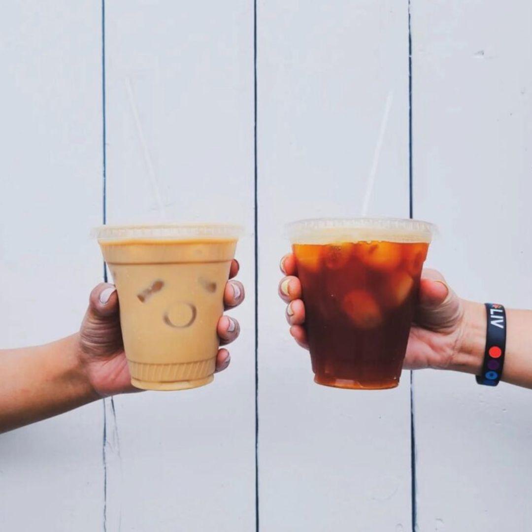 two hands holding iced coffees
