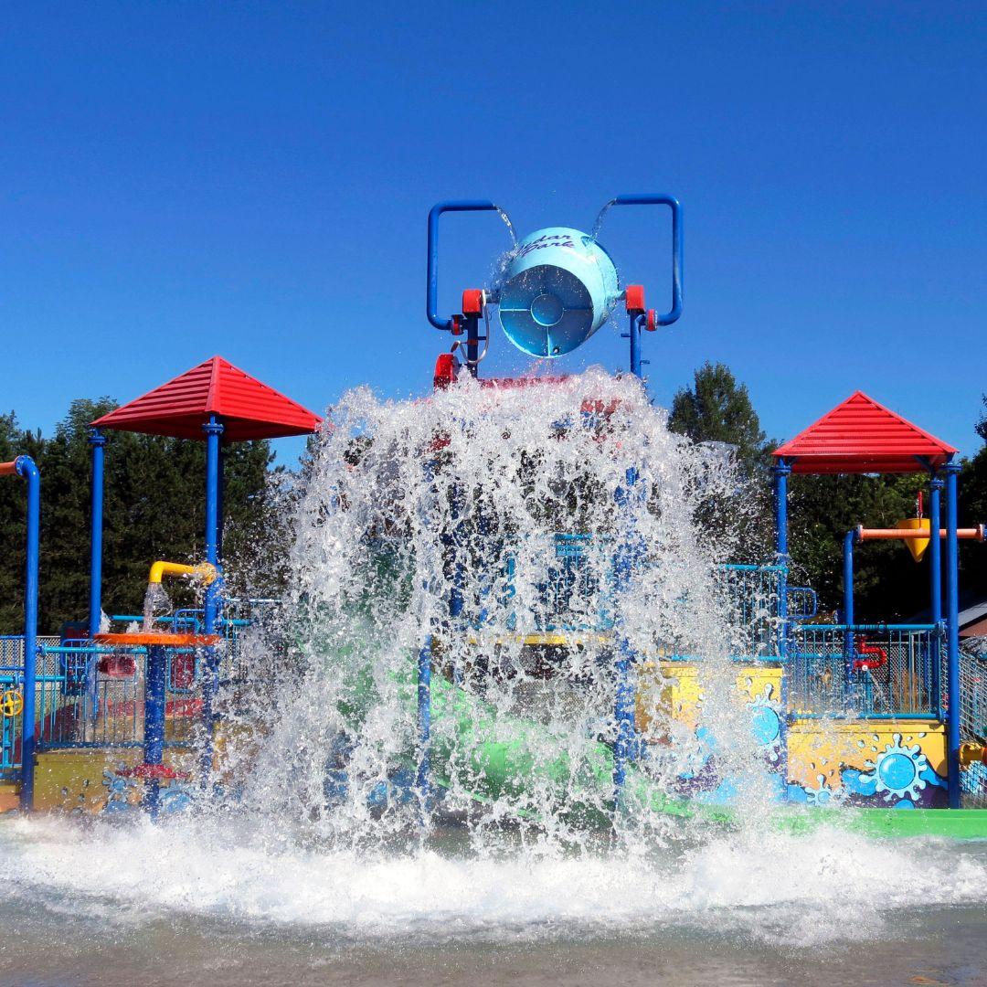 large splash pad park with water pouring out of a giant bucket