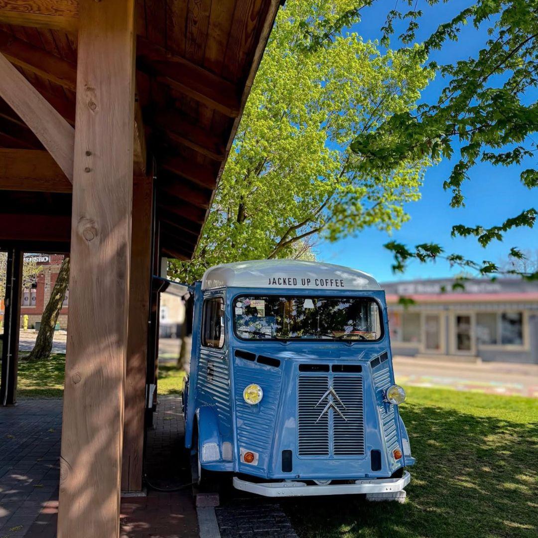 Blue coffee truck parked in a park.