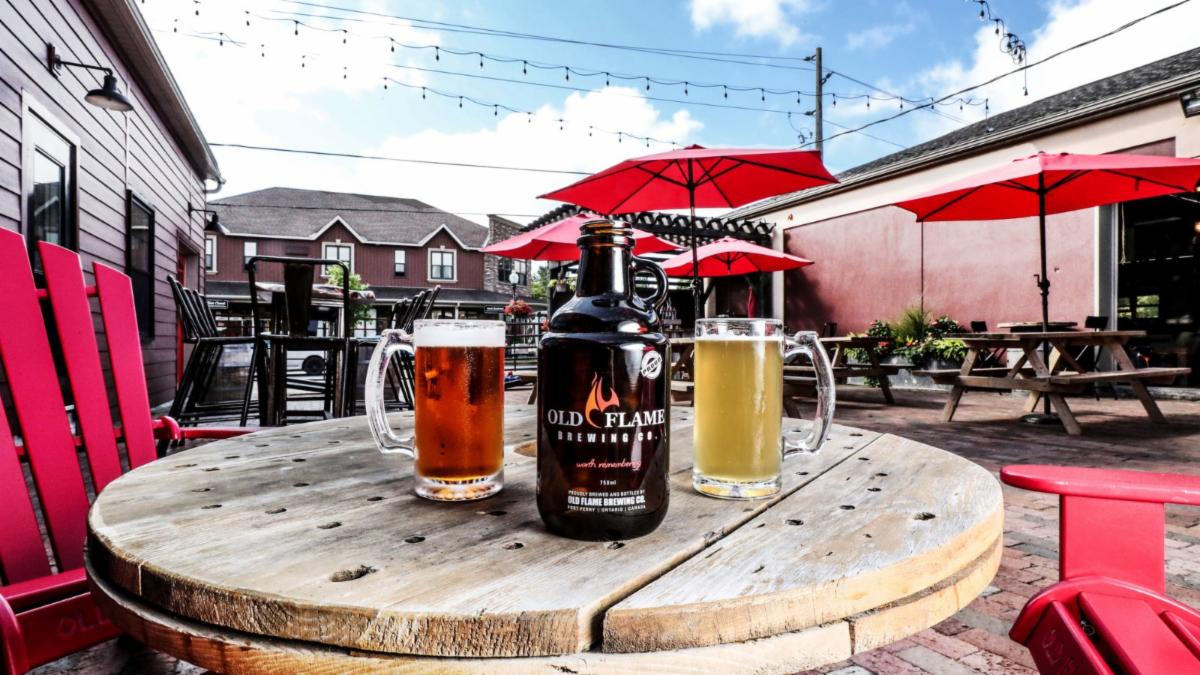 outdoor patio with two mugs of beer and a bottle on a table