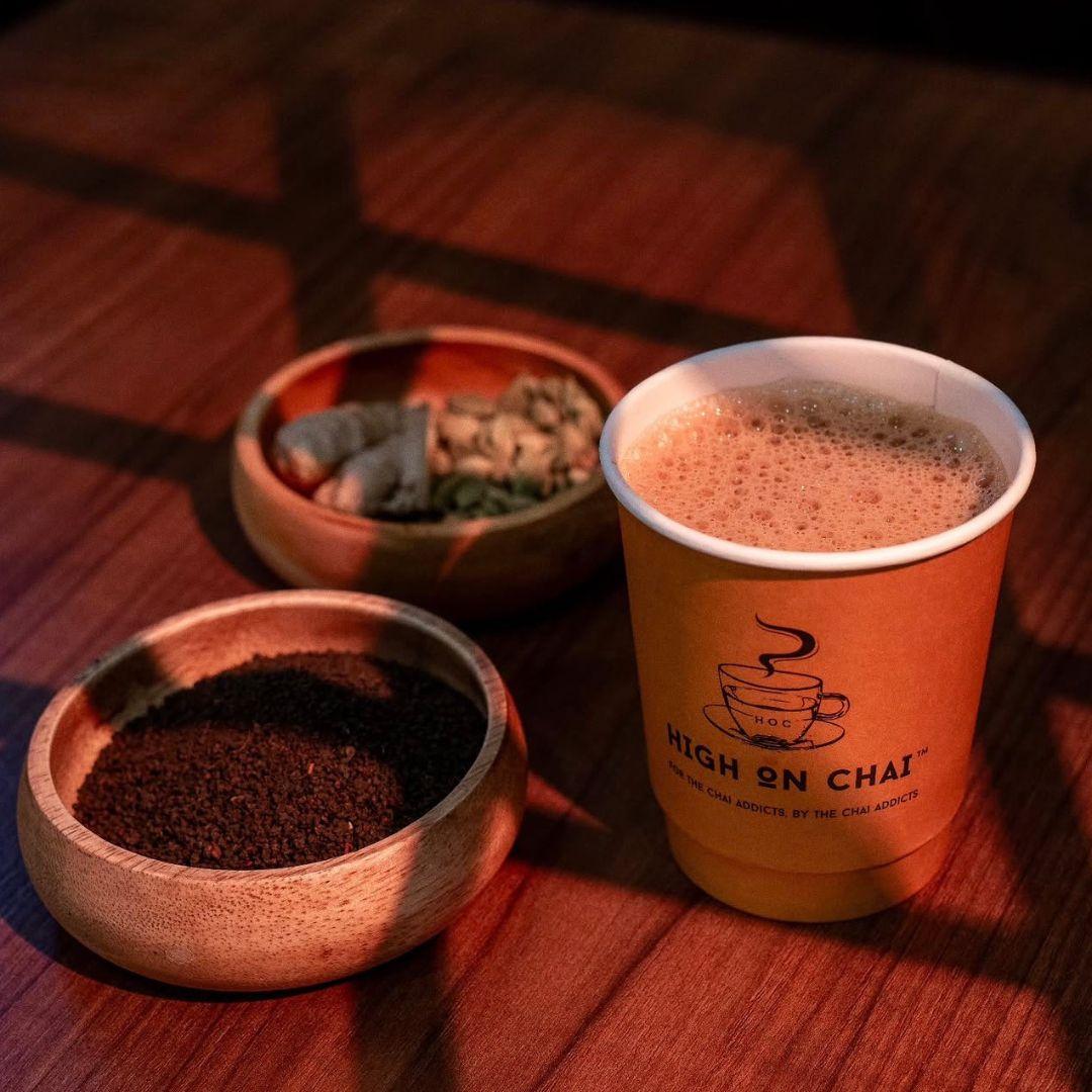 cup of chai beside two bowls of spices