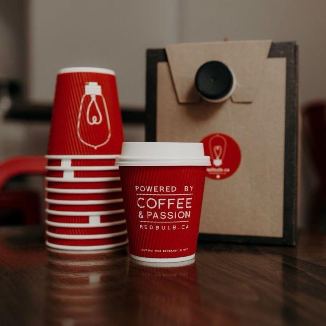 stacked paper coffee cups beside a paper coffee cup with a lid