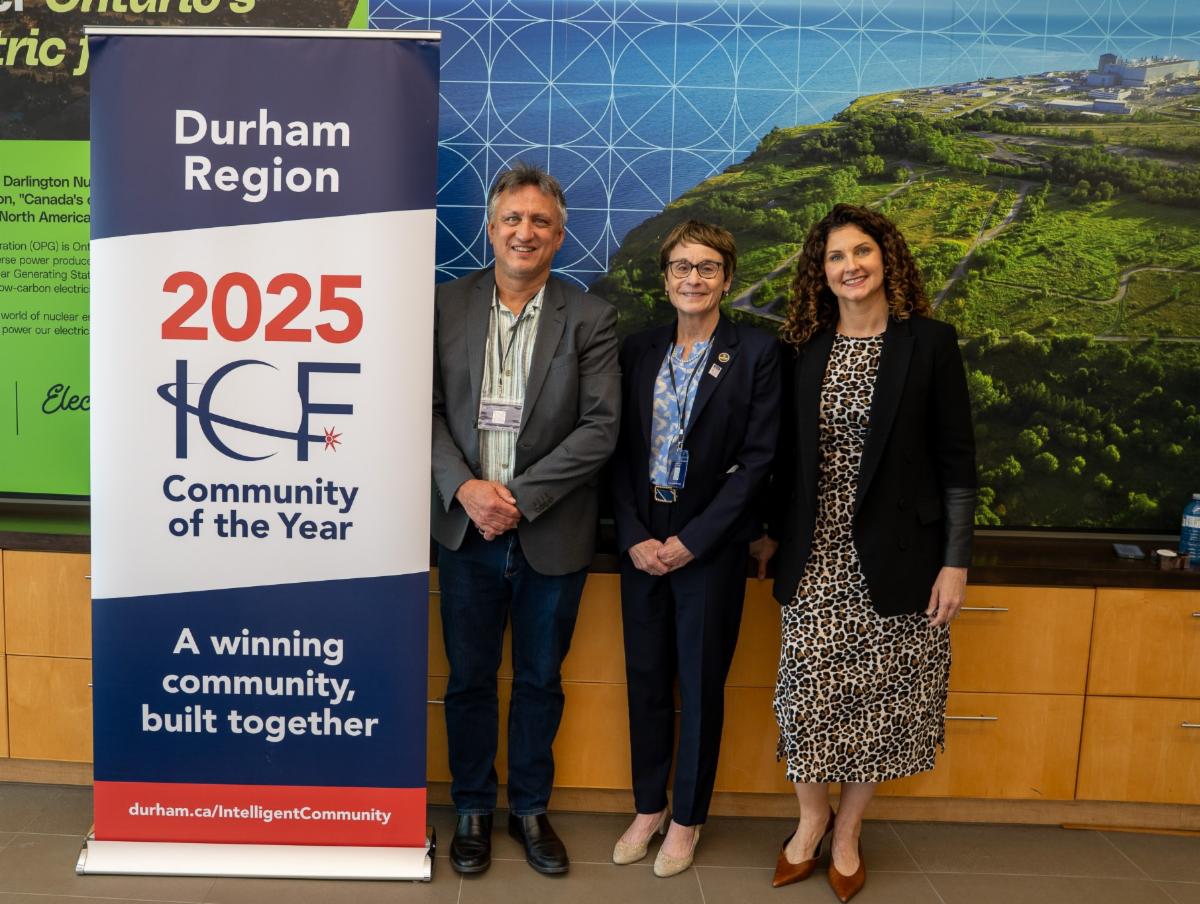 two women and a man stand beside a poster recognizing Durham Region as the 2025 ICF Community of the Year