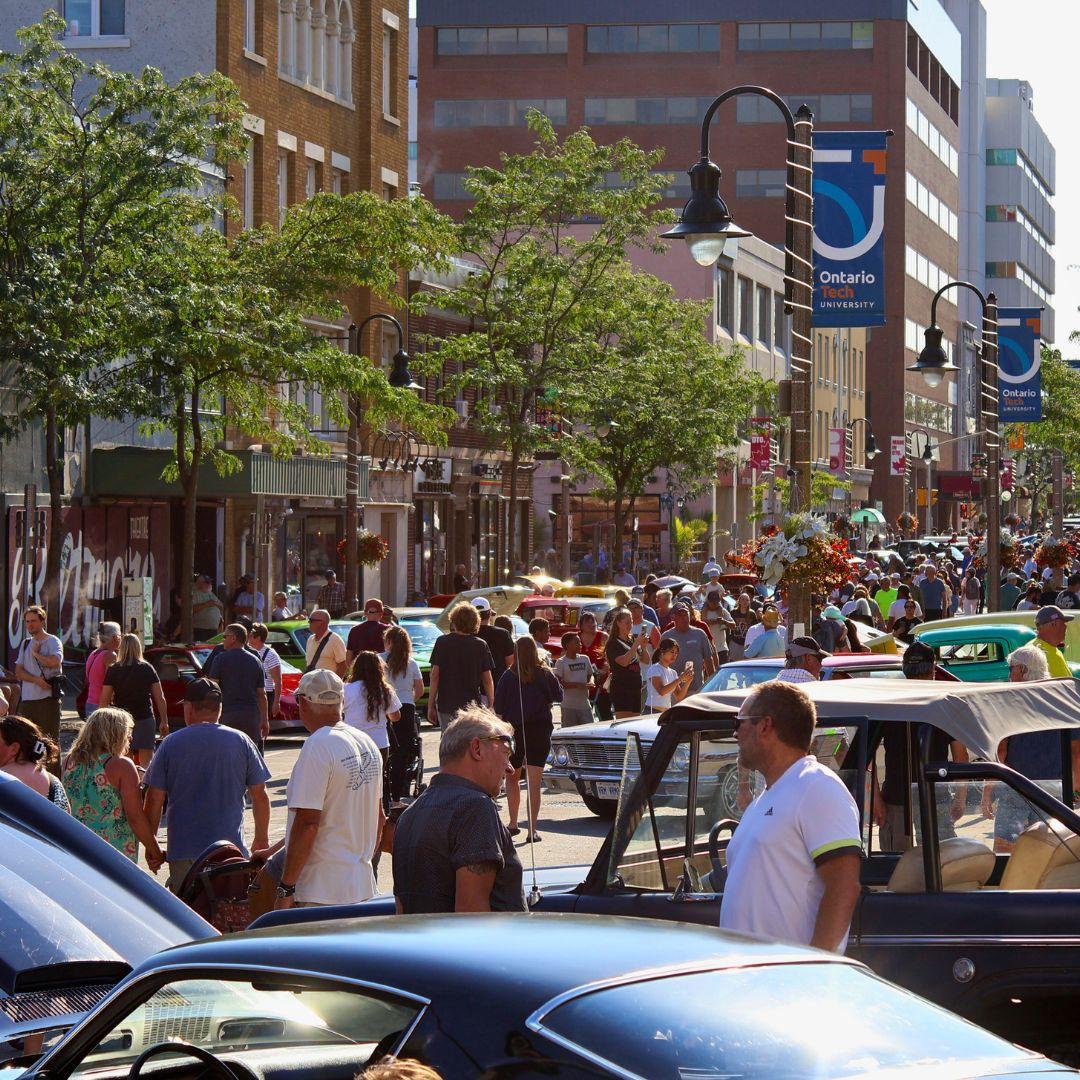 downtown street with old cars on display and crowds of people