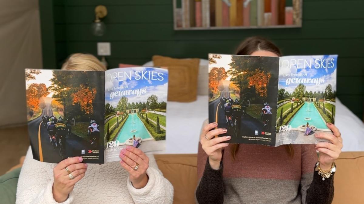 Two people holding copies of a magazine in front of their face