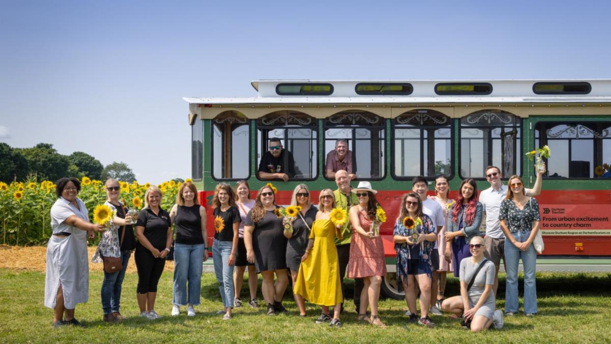 group of people stand in front of a trolley at a sunflower farm