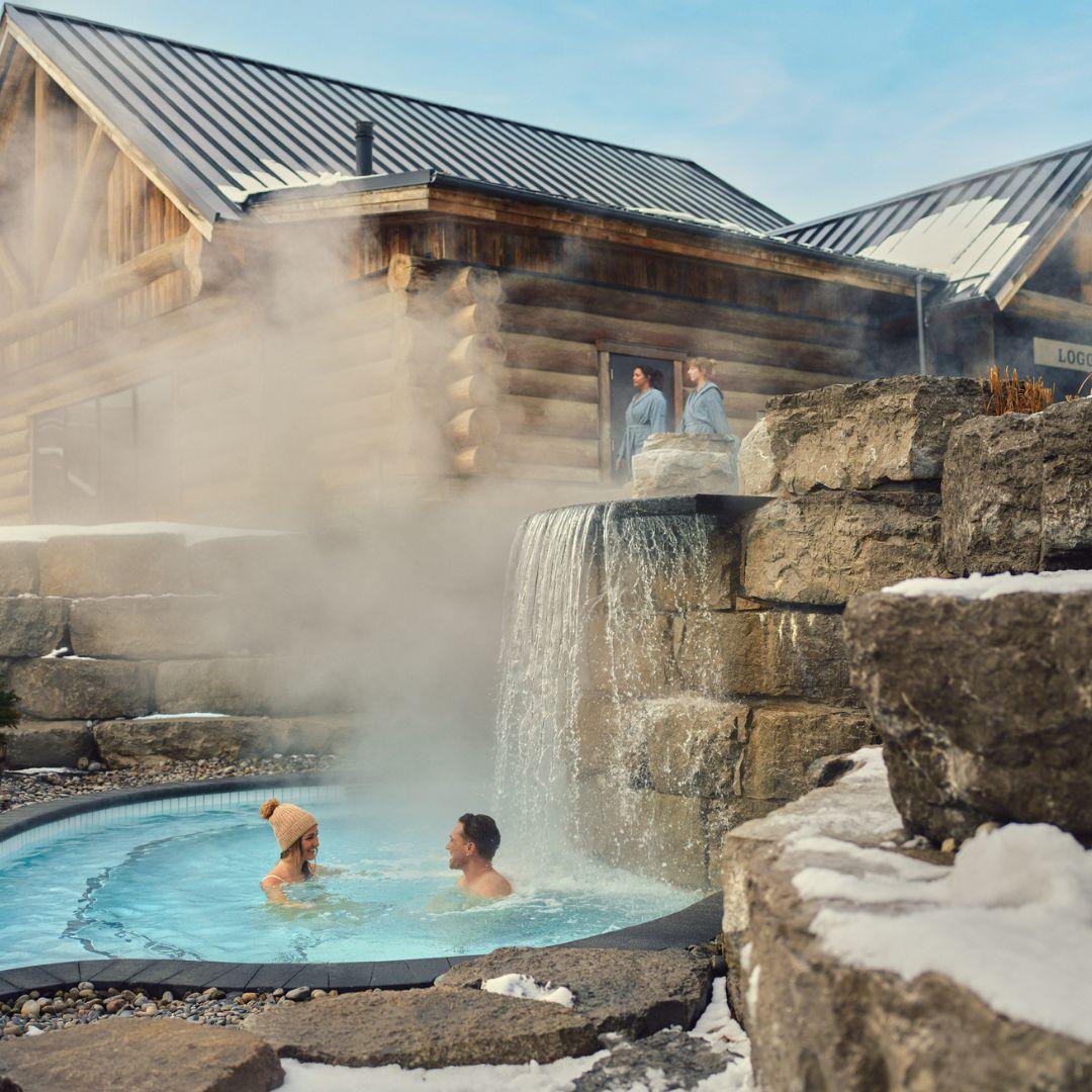 couple sitting in an outdoor hot tub at spa in winter