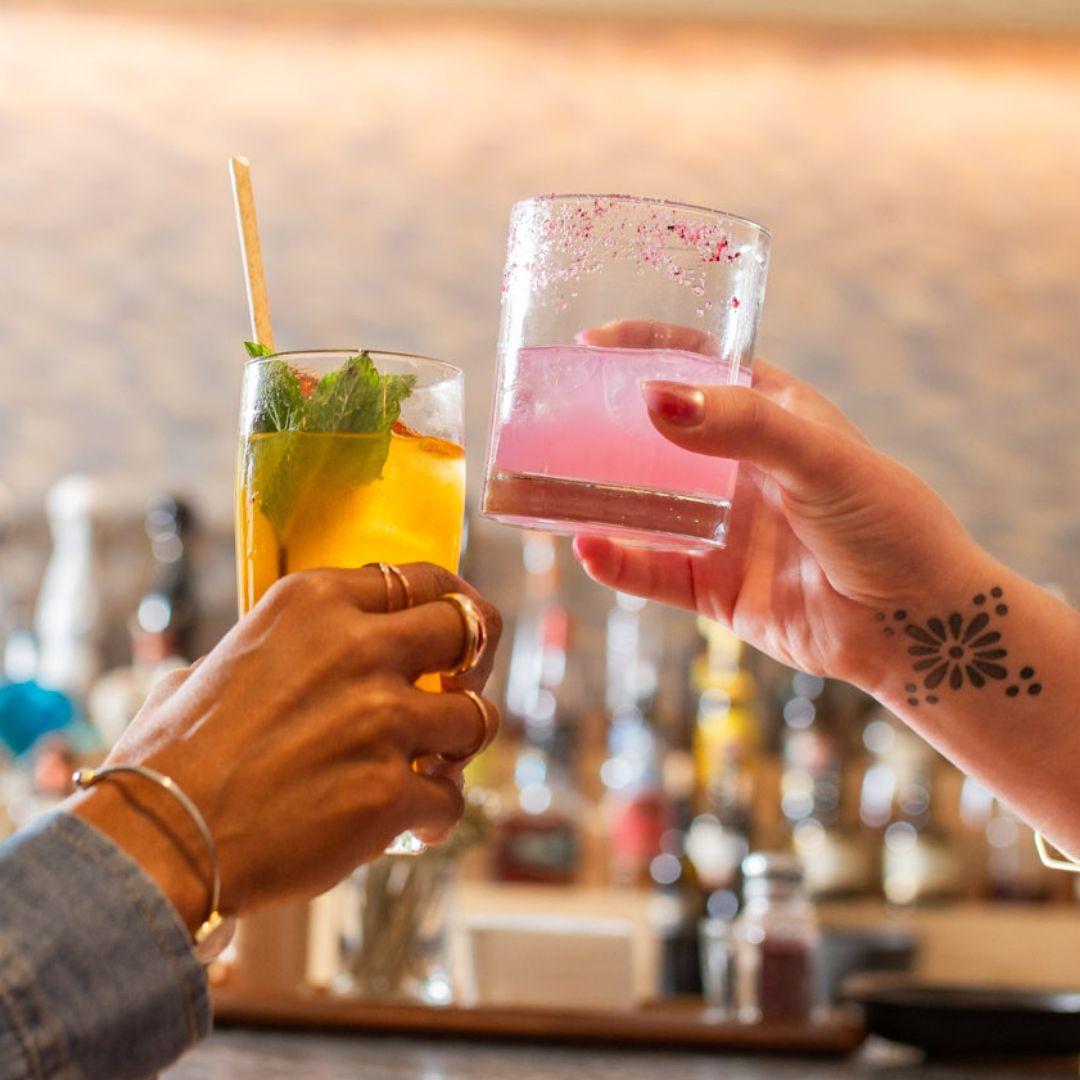 two hands holding up drinks