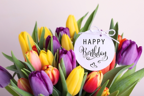 Beautiful bouquet of tulip flowers with Happy Birthday card on light background_ closeup