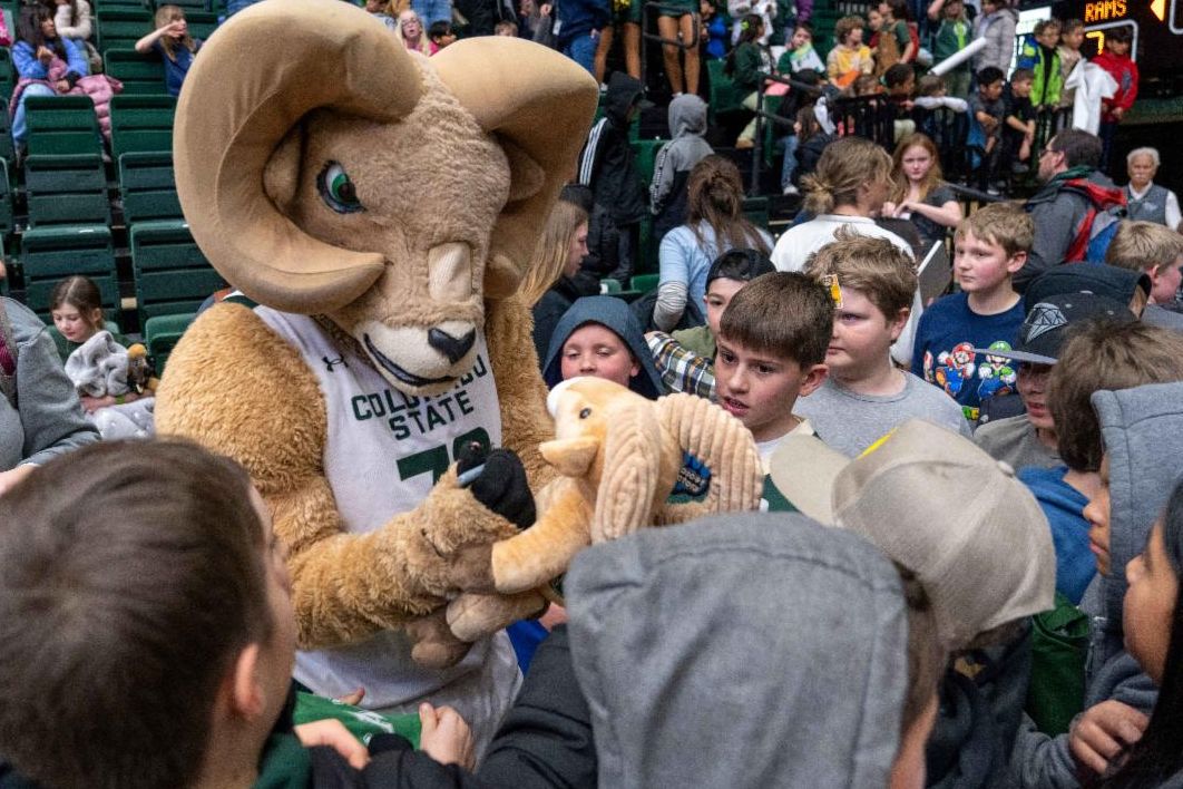 A group of children huddle around the CSU Cam the RAM mascot while he signs autographs.