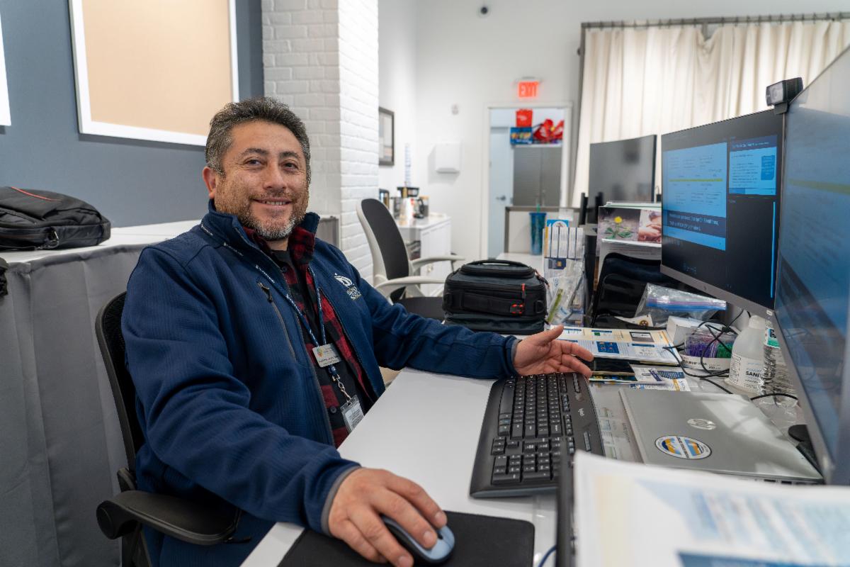 Portrait photo of a man seated at a desk working on a computer.