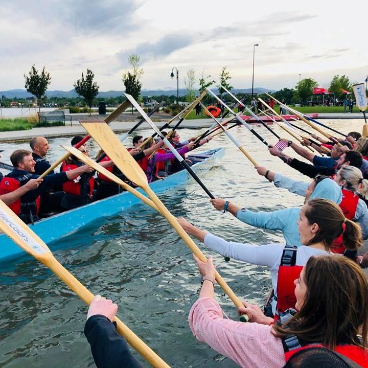two dragon boats side by side, with rowers touching paddles across the water