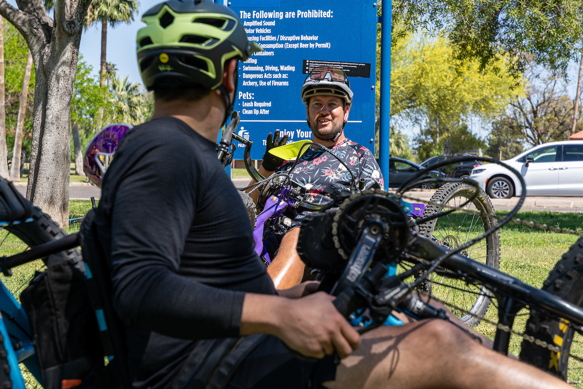 student in recumbent adaptive mountain bike looking over at instructor
