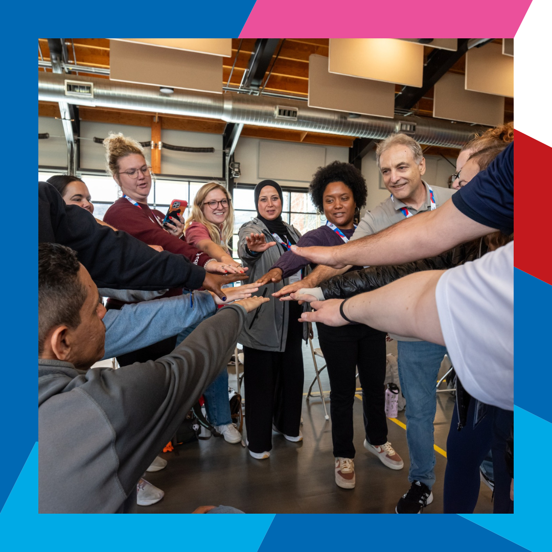 Group of conference attendees in a para cheer session gathered in a circle with hands outstretched meeting in center of circle 