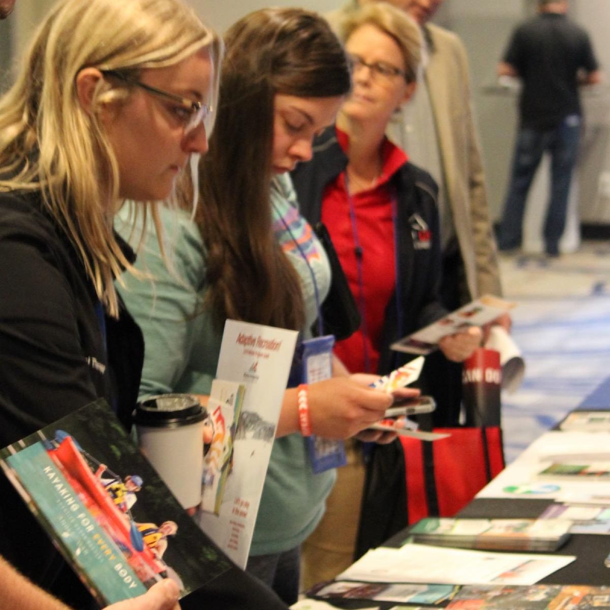 Education Conference Attendees picking  up information and pamphlets at table