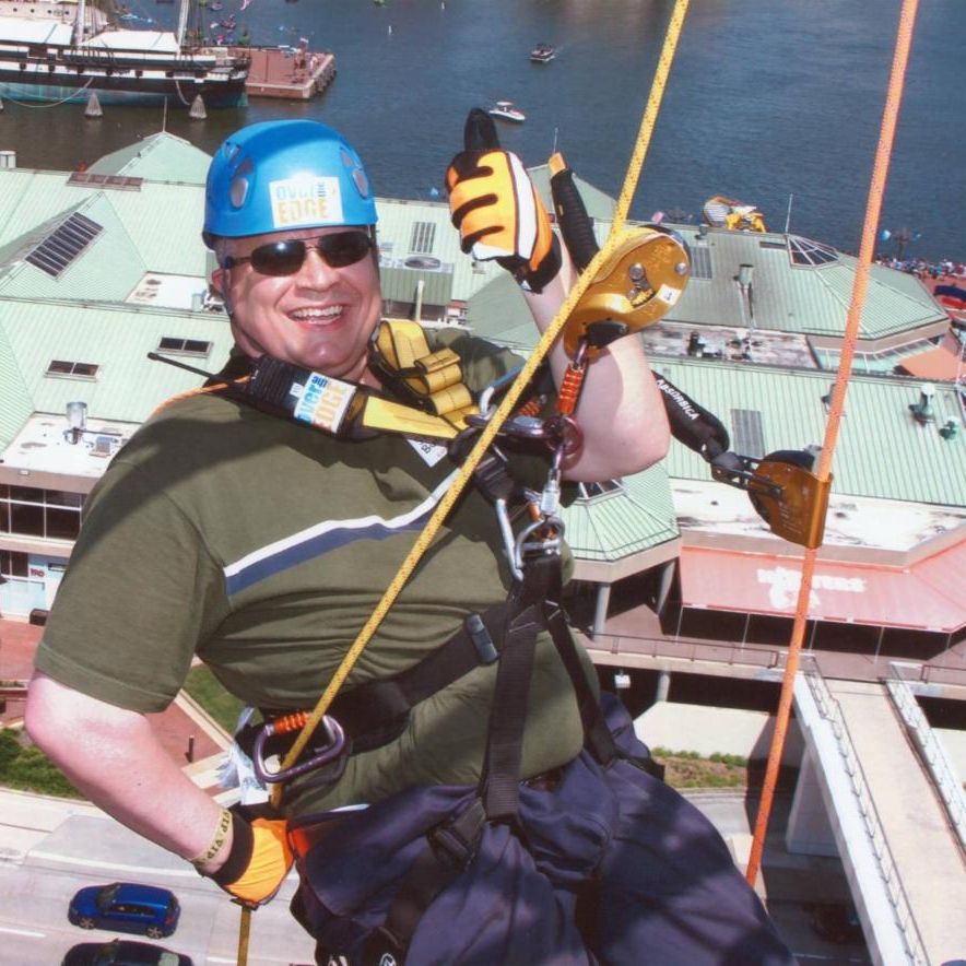 Photo of Shuan Butcher repelling off a building next to a body of water