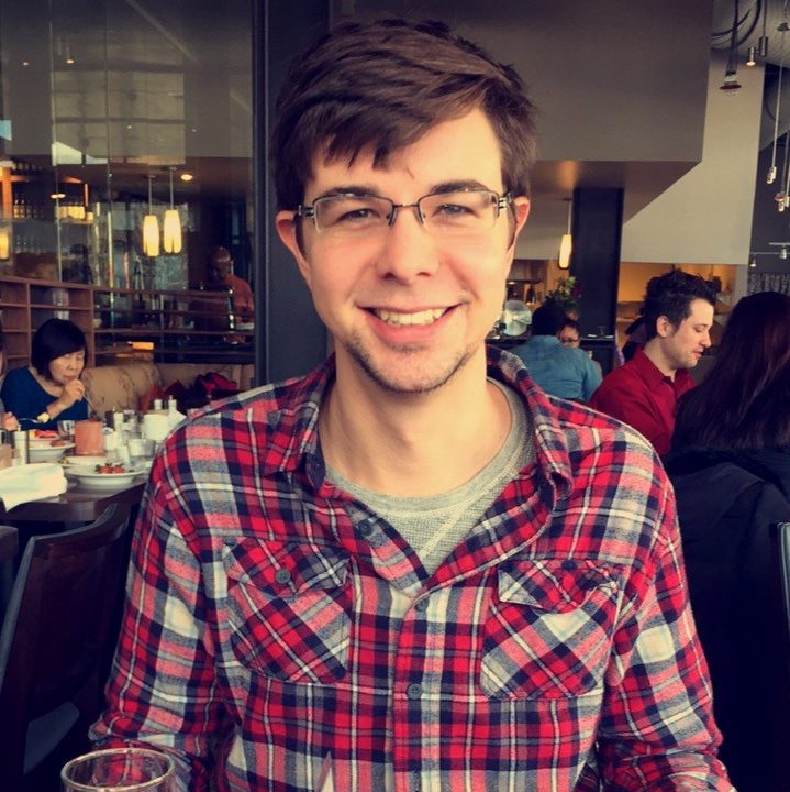 Headshot of James Arnold wearing red and white plaid shirt and glasses