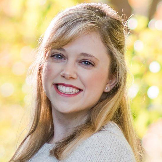 Woman smiling in front of foliage background