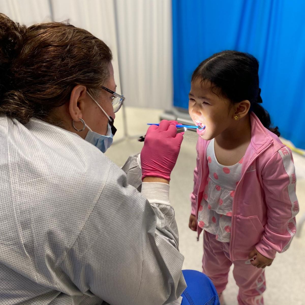 A dentist screens a child's mouth for decay