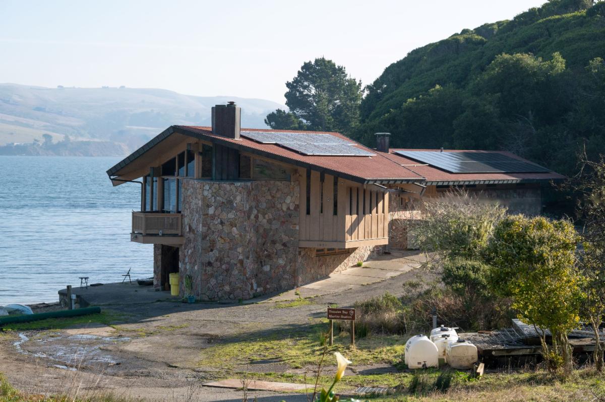 A view of a large house with brick walls and solar panels overlooking a bay.