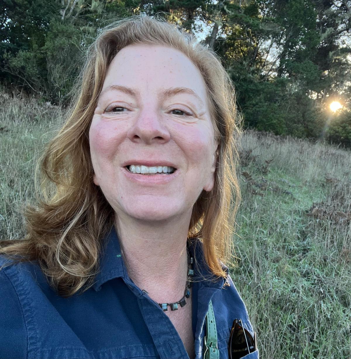 Donna wears a blue shirt and smiles at the camera
