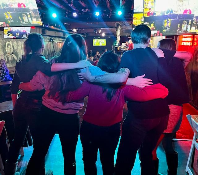 Photo from end of semester gathering of students embracing in a group hug