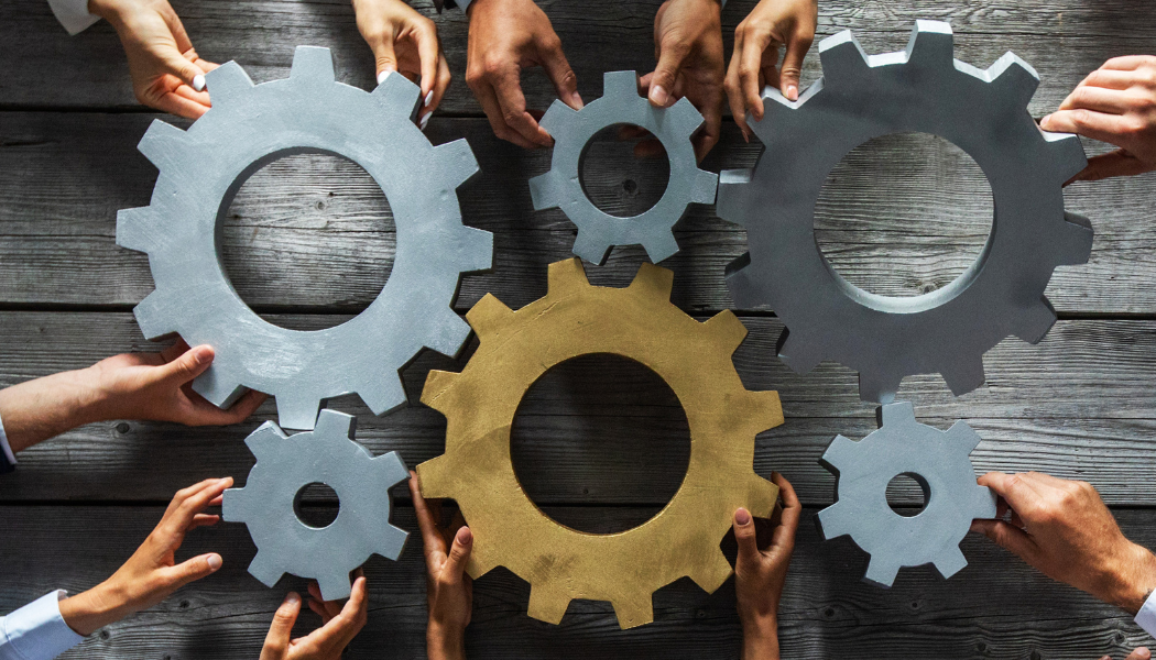 cogs being turned by many hands
