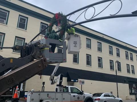 Employees in bucket truck hanging holiday wreaths 