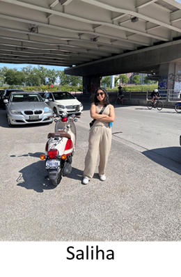 Young brown woman with dark hair stand with arms crossed next to an e-scooter