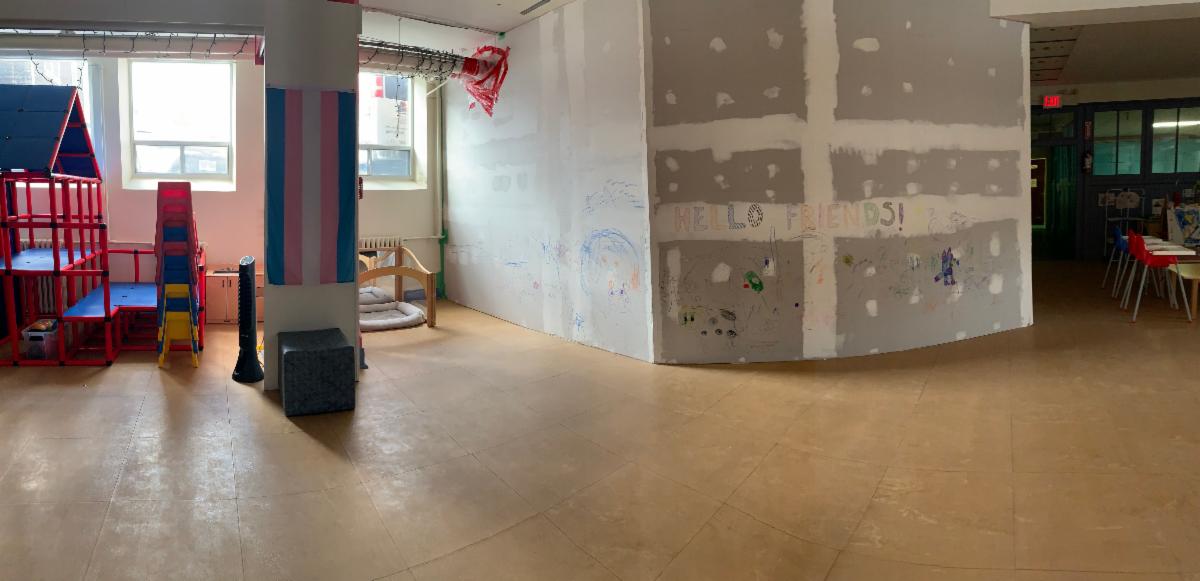 this image depicts a space where children's play equipment is stored to the left and a large unfinished wall has been built to enclose a separate space