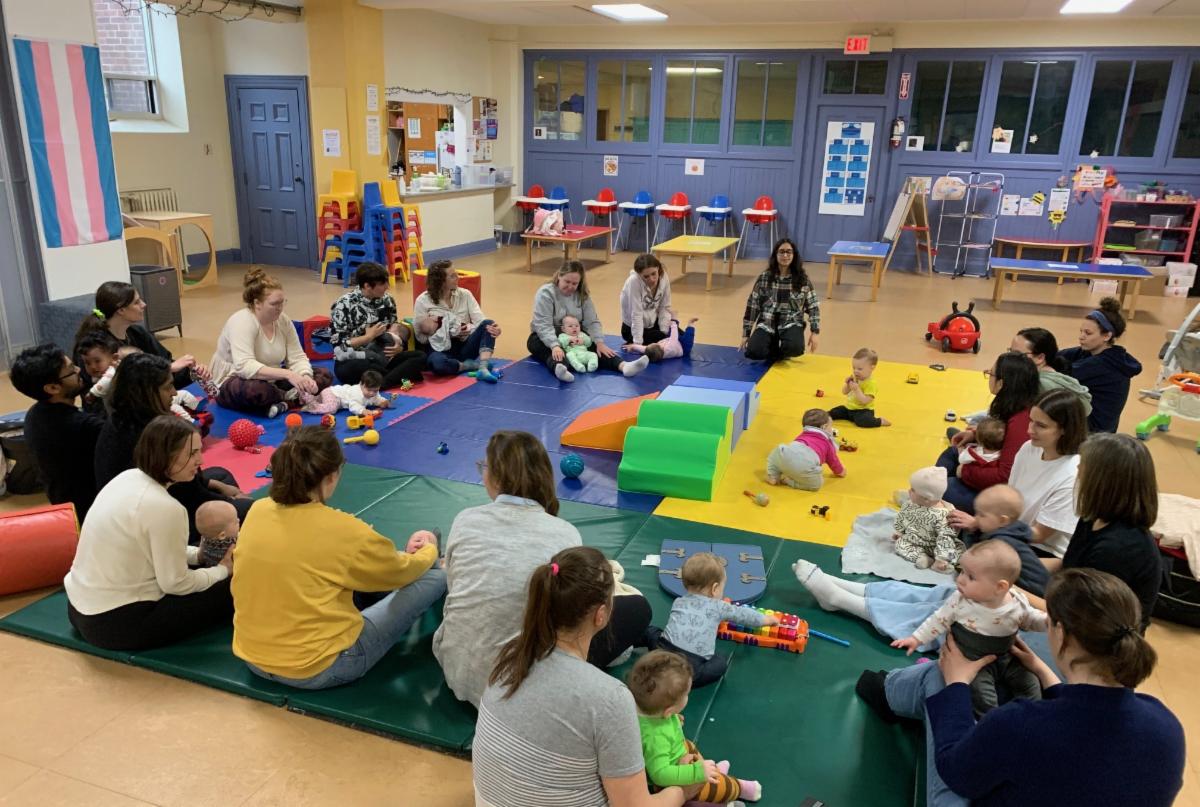 parents sit in a large circle with their babies on the floor