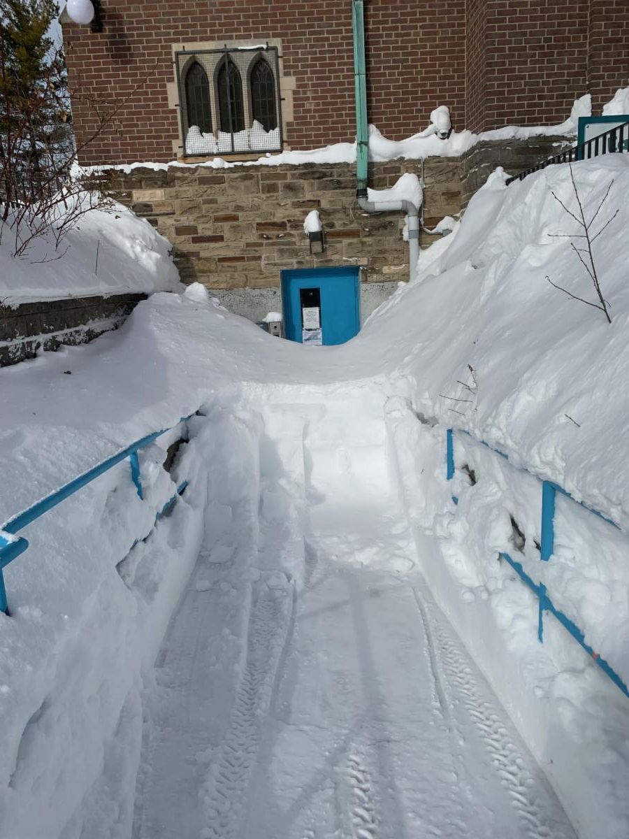 a brick building with a blue door and snow so deep it covers the bottom three quarters of the door