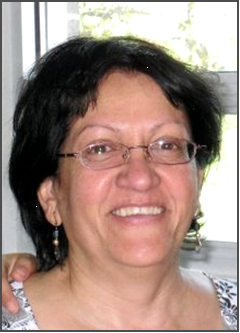 middle eastern woman wearing glasses smiles brightly at the viewer