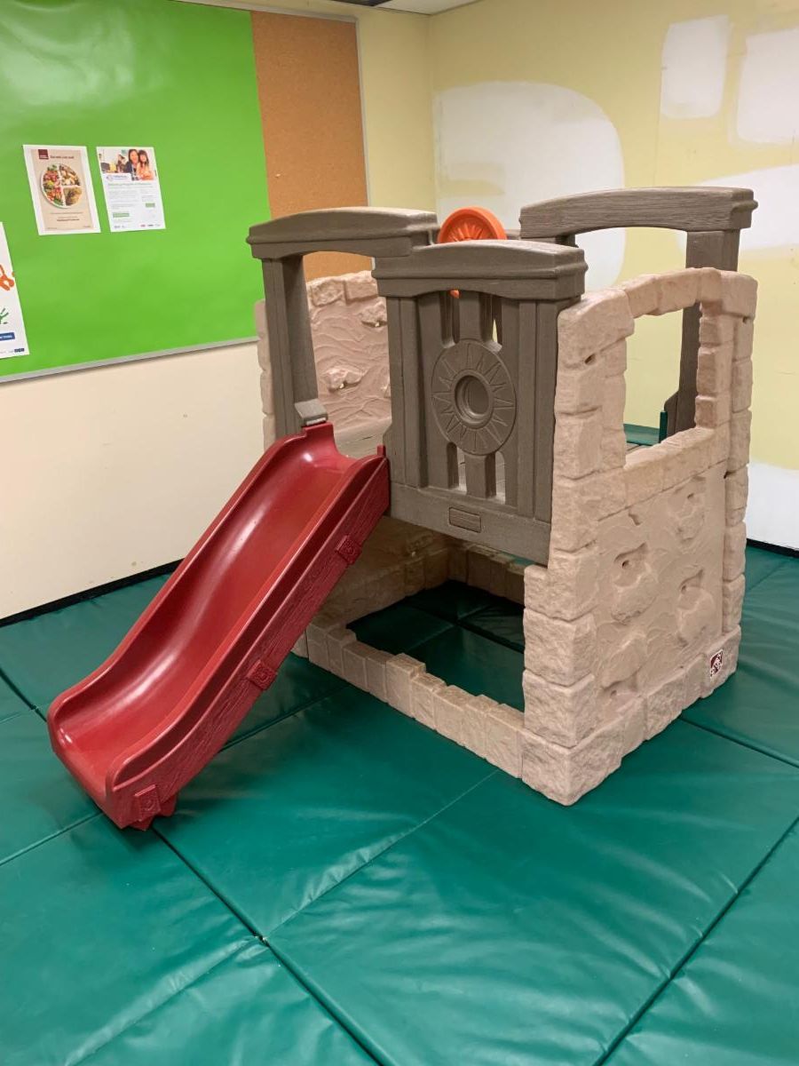 children's climbing apparatus with a slide on a green safey mat